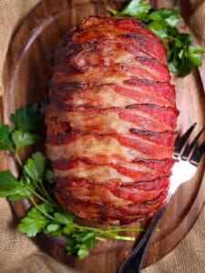 Overhead shot of Bacon-Wrapped Meatloaf on an oval wood serving board.