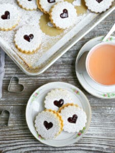 Nut-Free Linzer Cookies on a small dessert plateserved with a cup of hot tea and jam.