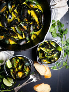 Two servings of Curry Coconut Mussels with sliced bread for dipping.