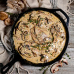 Pork chops bathed in creamy mushroom sauce with mushrooms scattered around.