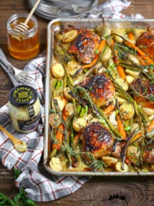A jar of Maille mustard next to oven roasted sheet pan chicken.