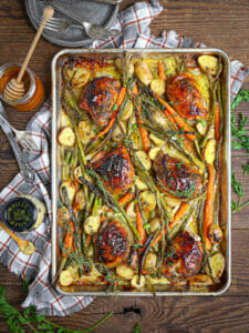 Sheet pan chicken with a mustard glaze with mustard and honey on the table.