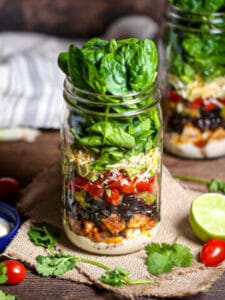 Layered Mexican Salad in a Jar with a jar of jalapeño ranch dressing on the table.