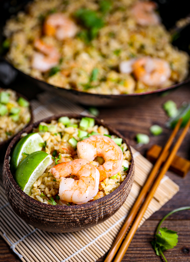 Shrimp Fried Rice with Pineapple in a wood bowl with shrimp and limes.