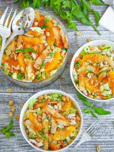 Chinese Chicken Salad in a glass bowl with two servings in a white bowls.