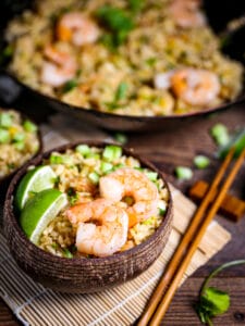 Shrimp Fried Rice with Pineapple in a wood bowl with shrimp and limes.