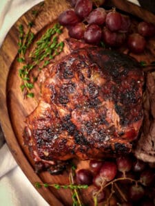 Close up of a braised lamb shoulder on a serving board ready tis be carved.