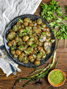 Grilled Potato Salad with scallions and herbs scattered around.