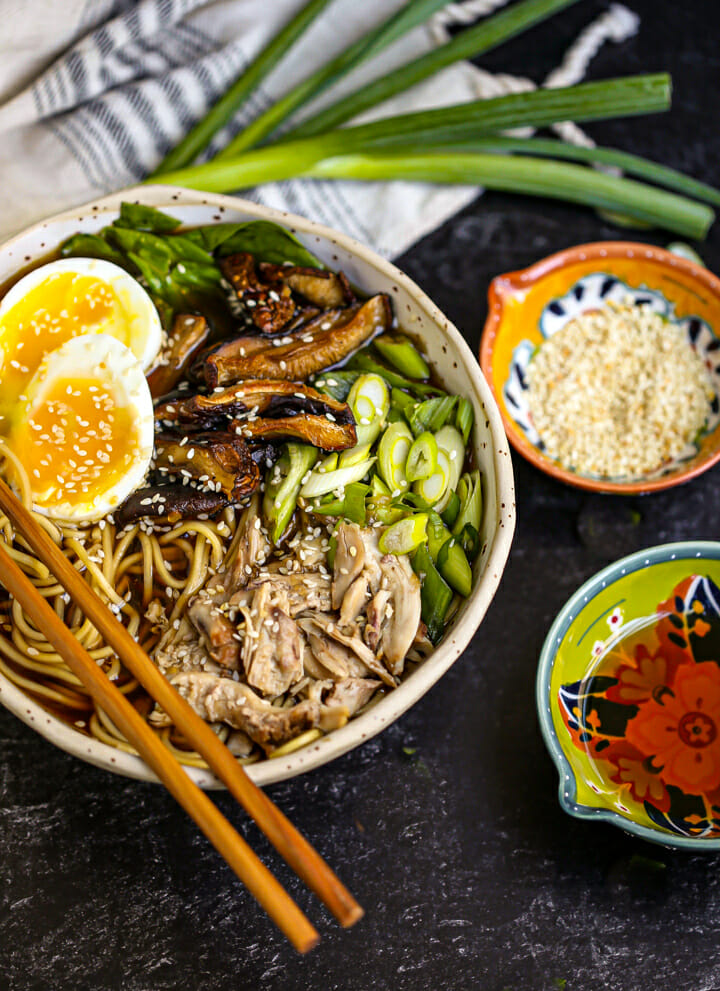 A bowl of ramen garnished and with an egg and sesame seeds and chopsticks laid across the bowl.