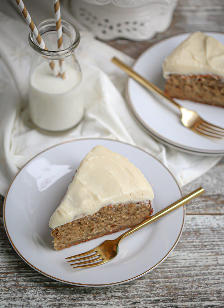 Slices of banana cake on white plates with gold forks and a glass of milk.
