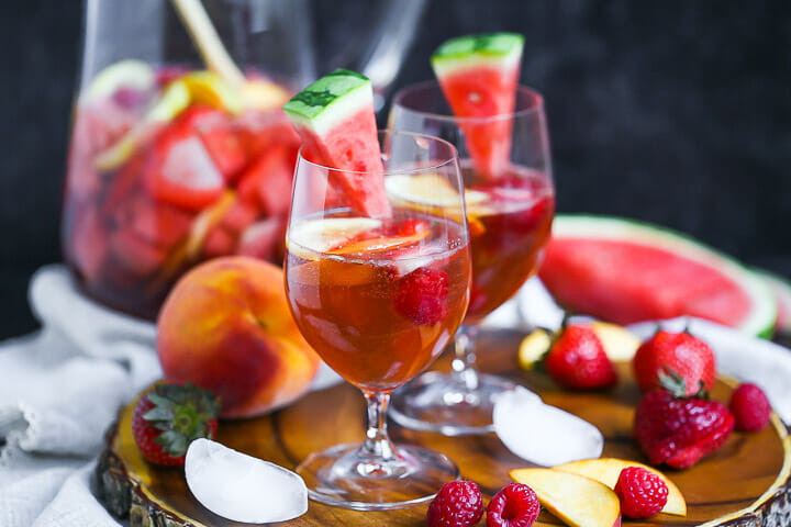 Close up of a glass of Easy Rosé Sangria with fruit scattered around.