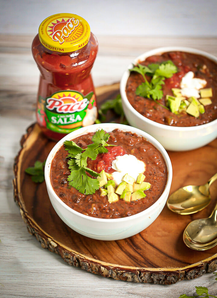 A bowl of Easy Black Bean Soup with salsa in the background.