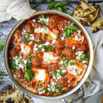 Overhead shot of Shakshuka with Lamb Meatballs topped with herbs and served with charred pita.