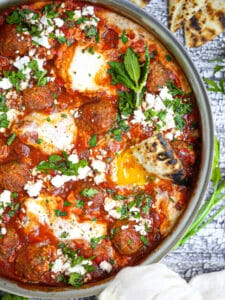 A piece of toasted pita dipped into a runny yolk in lamb shakshuka.