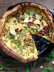 Overhead shot of a dutch baby with a slice cut out and served on a plate.