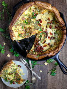 Overhead shot of a dutch baby with a slice cut out and served on a plate.