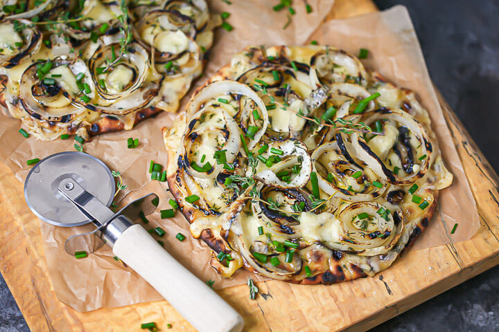 Close up of onion and swiss flatbread ready for slicing.