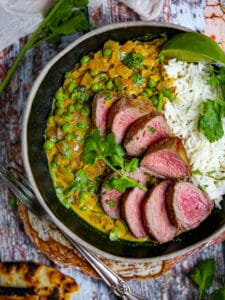 Sliced lamb medallions served with coconut curry sauce and rice.