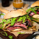 A grilled steak sandwich topped with arugula.