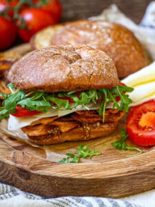 An Italian BLT and all the fixings on a round wood board.