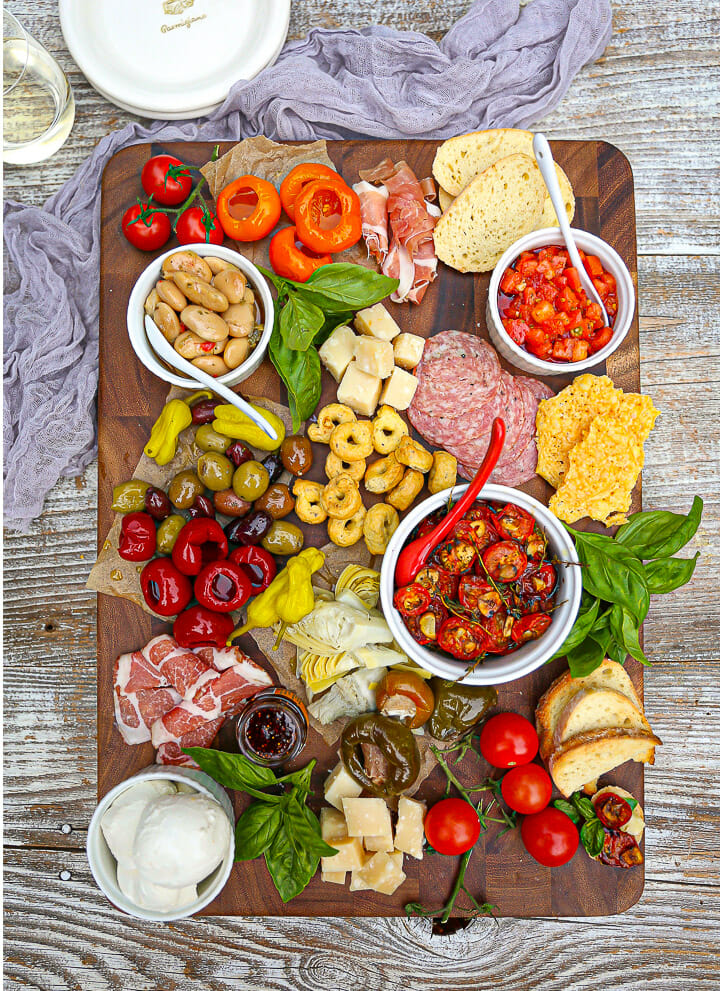 Overhead shot of an Italian grazing board filled with cheese, olives, meats, veggies and roasted tomatoes.