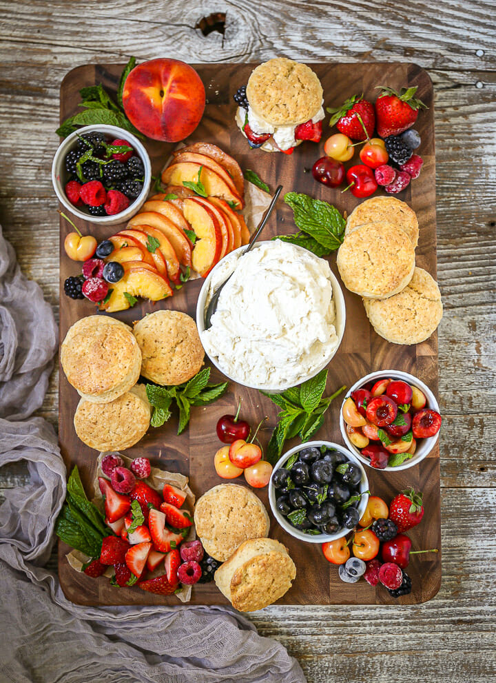 Overhead shot of a shortcake dessert board topped with biscuits, whipped cream fruit and berries.
