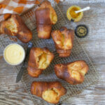 Honey Mustard Popovers out of the oven and resting on a baking rack with butter and mustard.