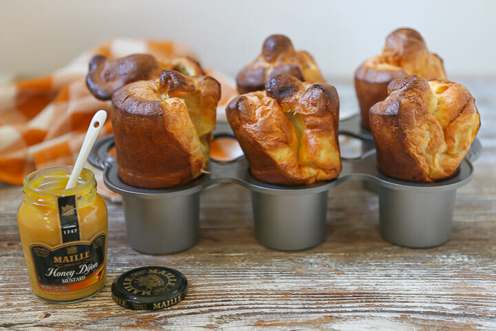 Popovers risen and golden in a popover pan with Maille Honey Dijon on the side.