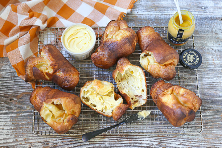Popovers on a baking rack with one split open and buttered.