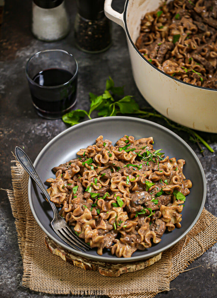 A serving of Beef Stroganoff ready for dinner with a glass of wine.