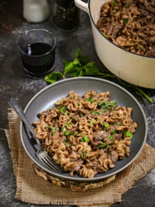 A serving of Beef Stroganoff ready for dinner with a glass of wine.