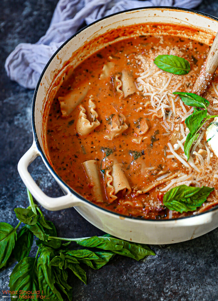 A pot of lasagna soup with basil scattered around.
