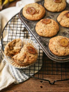 Banana muffins on a cooling rack with one muffin pulled apart.