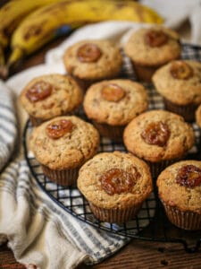 Banana muffins on a cooling rack topped with caramelized banana slices.
