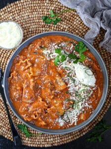 Overhead shot of a bowl of lasagna soup on a wooded beaded placemat.