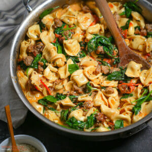 A pan of Creamy Sausage Tortellini with Spinach and Tomatoes just off the stove.