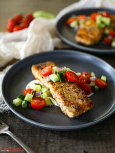Close up of a serving of Everything Bagel Salmon with Tomato Cucumber Salad.