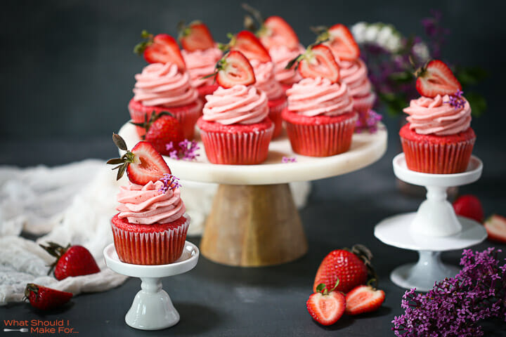 An arrangement of strawberry cupcakes on a cake plate and mini cupcake stands.